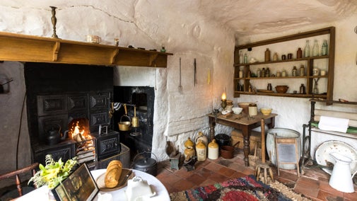 The front room inside Fletcher's Cottage at Kinver Edge and the Rock Houses, Staffordshire. A welcoming fire burns in the lead range. The interior has been recreated in the Victorian style.